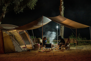 deux personnes préparant un repas à côté d'une tente
