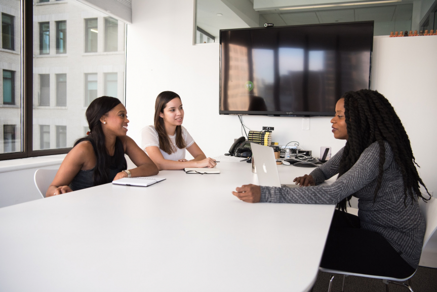 trois personnes discutant autour d'une table au travail